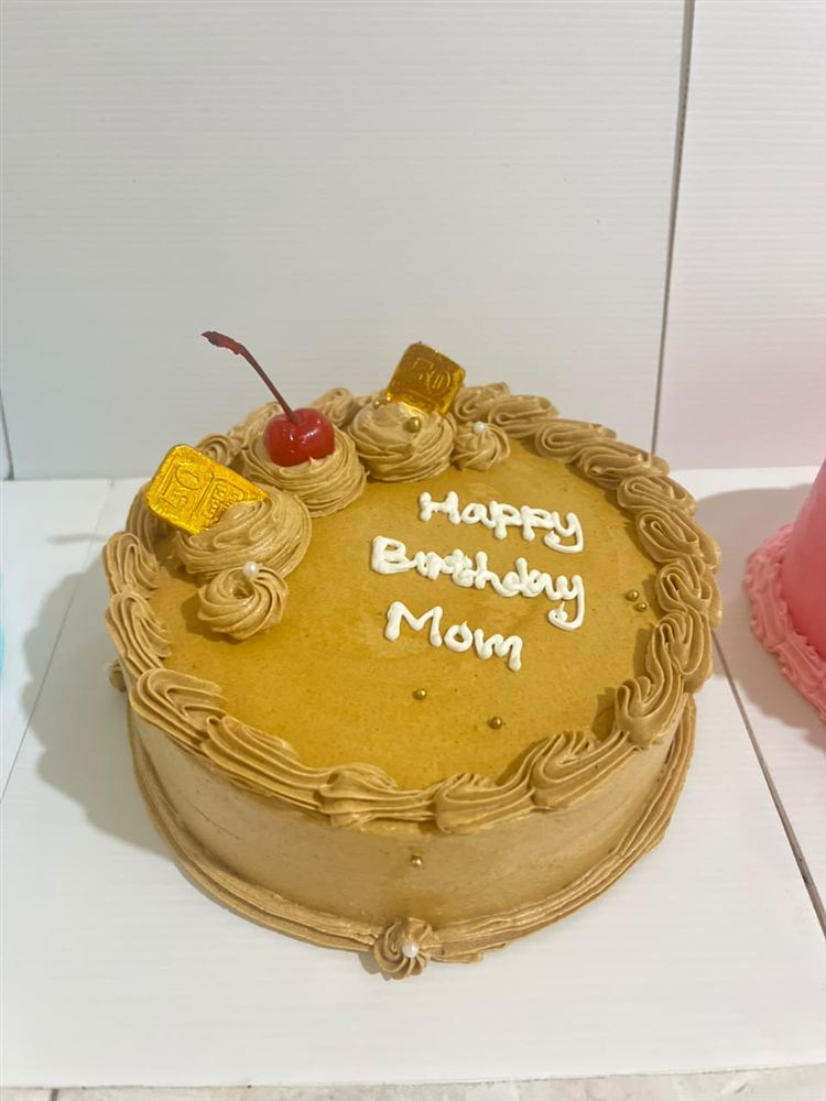 Kue ulang tahun krim karamel dengan tulisan Happy Birthday